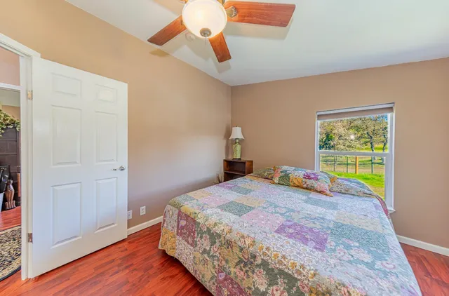 a bedroom with a bed a large window with wooden floor and a rug