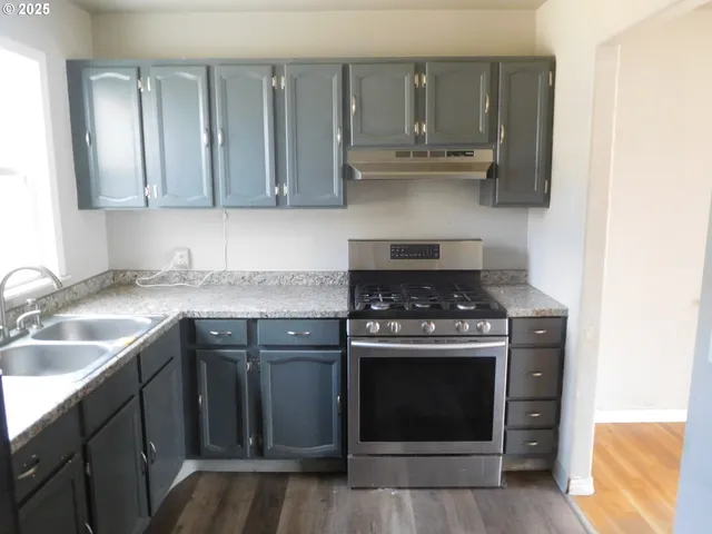 a kitchen with granite countertop a sink stove and cabinets