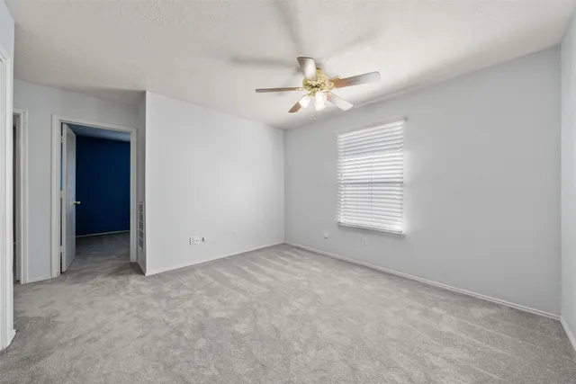 an empty room with windows and fan