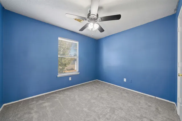 an empty room with a window and a fan