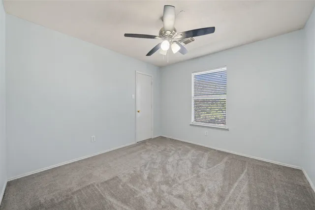 an empty room with a chandelier fan and windows
