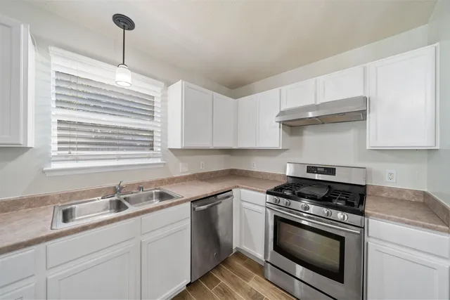 a kitchen with cabinets appliances a sink and a window