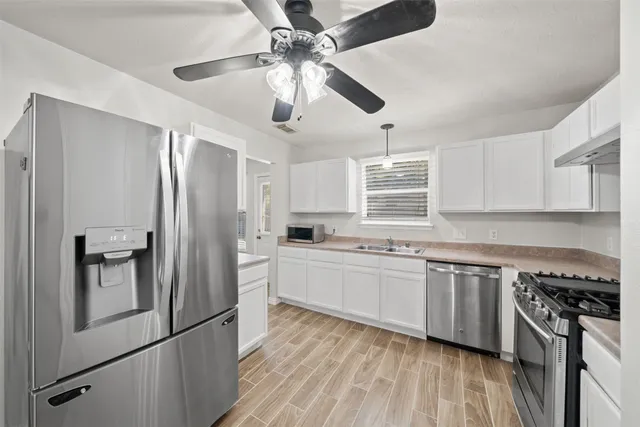 a kitchen with stainless steel appliances granite countertop hardwood floor sink stove dining table and chairs