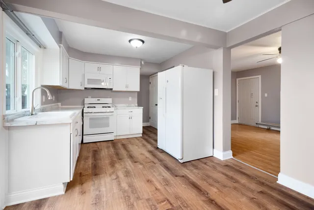 a kitchen with a refrigerator a stove top oven and wooden floors