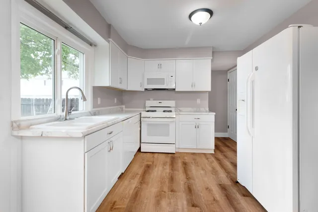 a kitchen with granite countertop white cabinets and white appliances