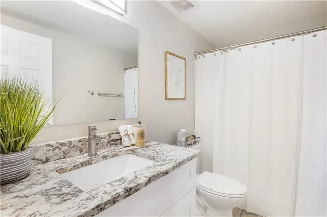 a en suite bathroom with a granite countertop sink and a mirror