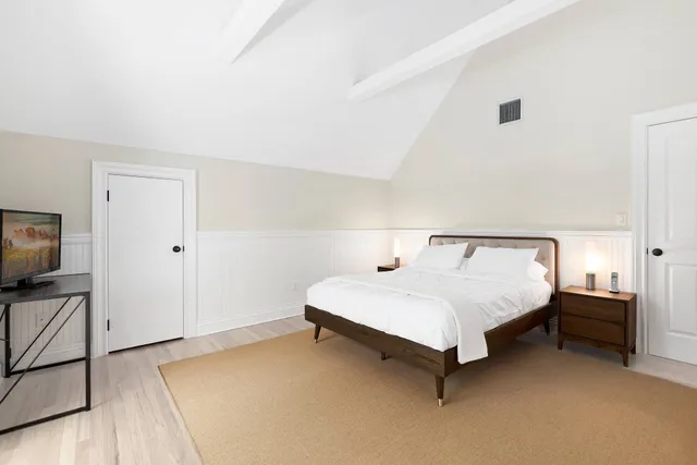 a bedroom with a bed and flat tv screen on the dresser