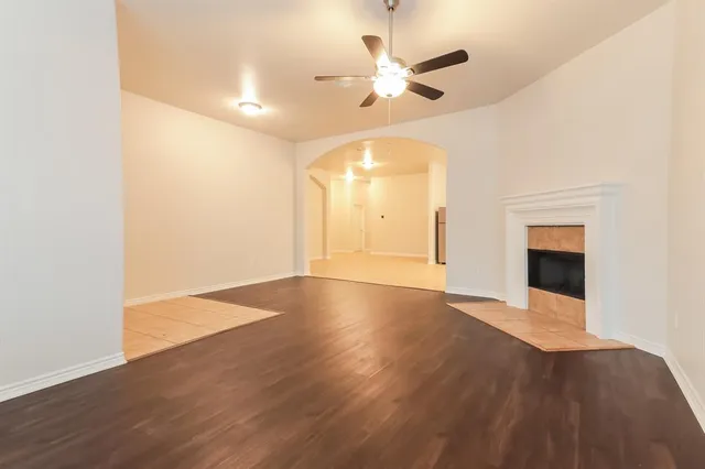 an empty room with wooden floor fan and windows