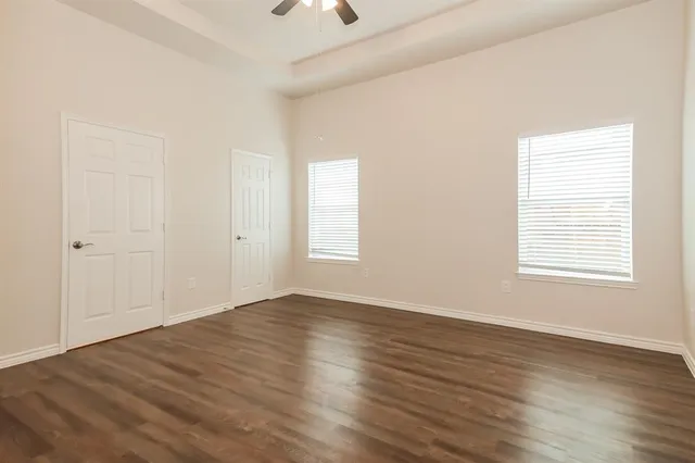 an empty room with wooden floor and windows