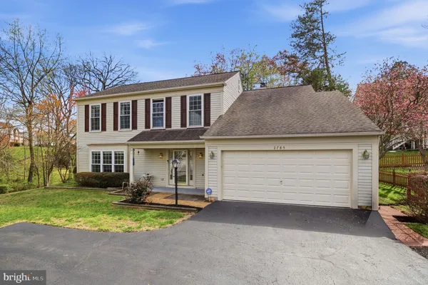 a front view of a house with a garden and trees