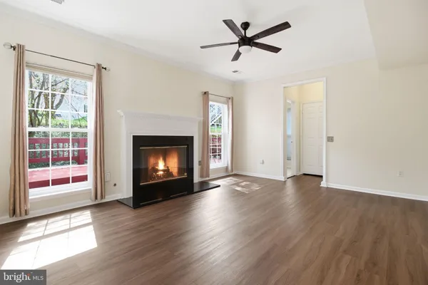 a view of an empty room with wooden floor fireplace and a window
