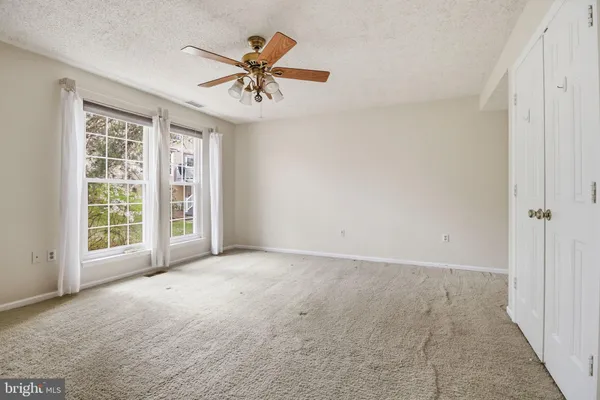 an empty room with windows and fan