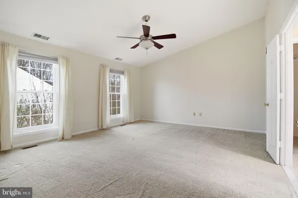 an empty room with closet and a ceiling fan