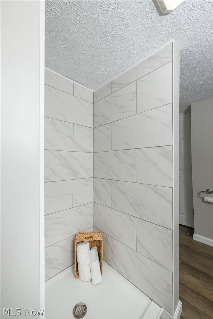 6484 Manchester Road Clinton, OH 44216 - Photo 18 of 21 Bathroom featuring a tile shower, hardwood / wood-style flooring, and a textured ceiling