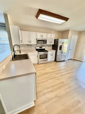 a kitchen with a sink a stove top oven and white kitchen