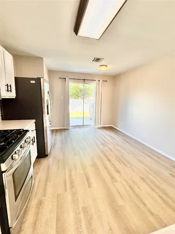 a view of a kitchen with wooden floor electronic appliances and windows