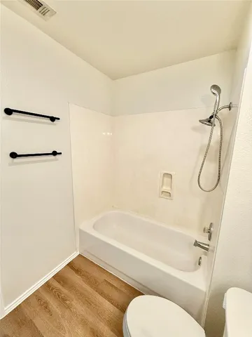 a bathroom with a granite countertop bathtub shower sink vanity and toilet