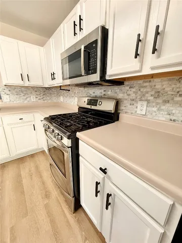 a kitchen with stainless steel appliances white cabinets and a stove top oven