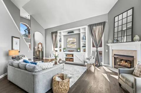 a kitchen with granite countertop a refrigerator a stove a dining table and chairs with wooden floor