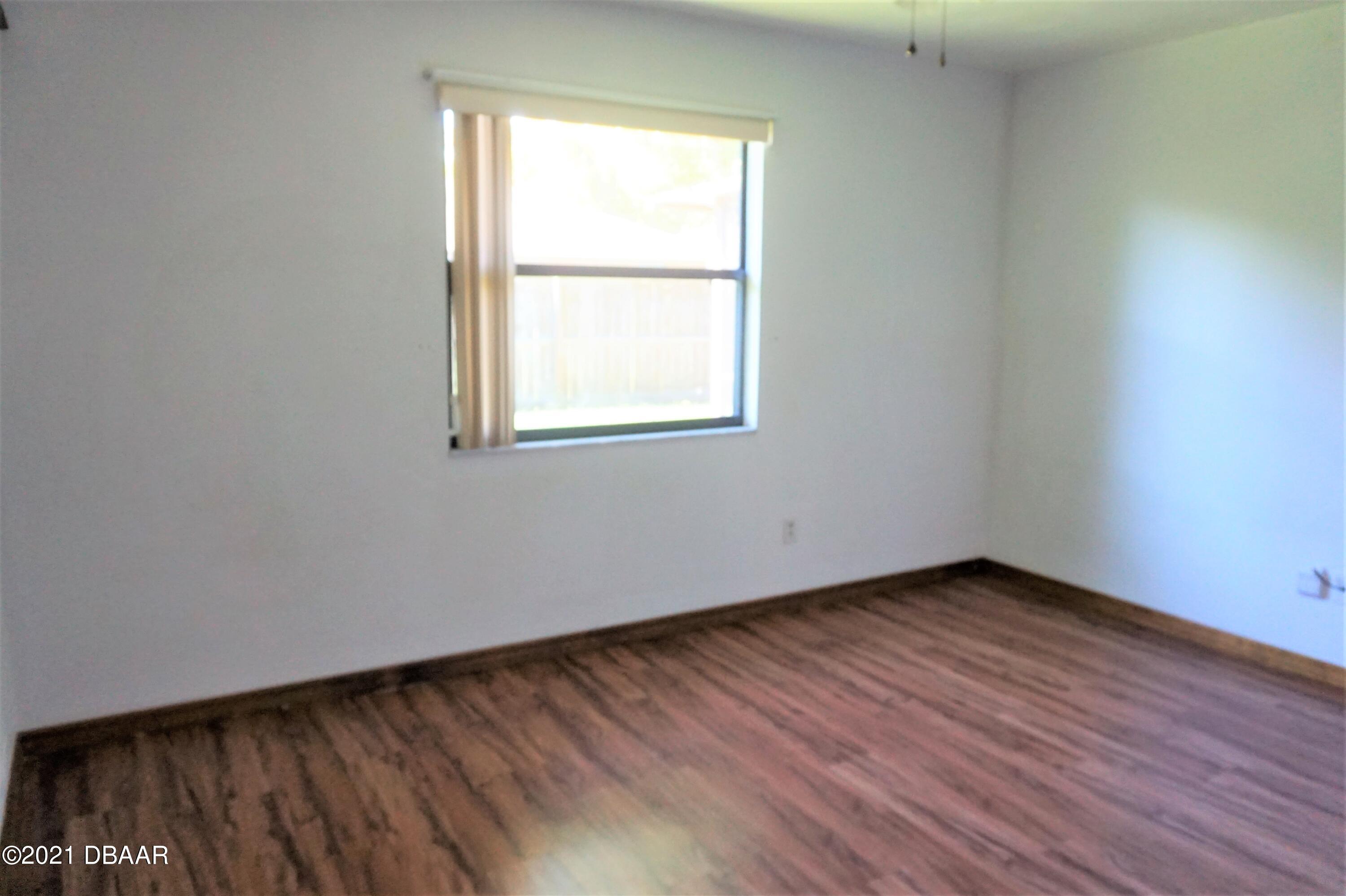 12 Charleston Square Ormond Beach, FL 32174 - Photo 17 of 26 an empty room with wooden floor and windows