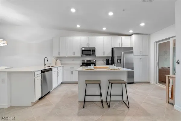 a kitchen with a sink a refrigerator and white cabinets