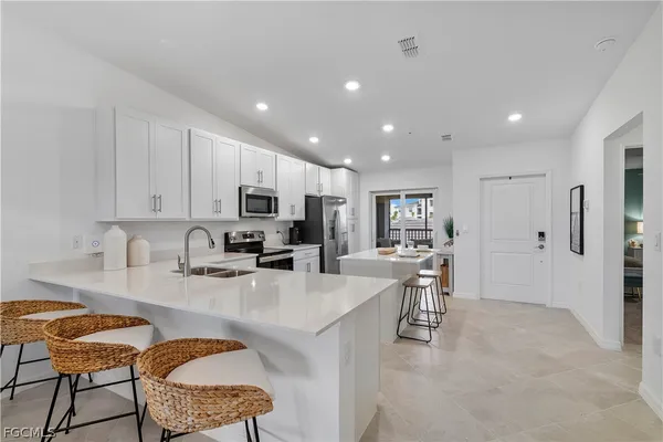 a kitchen with stainless steel appliances granite countertop a stove top oven a sink a refrigerator and white cabinets