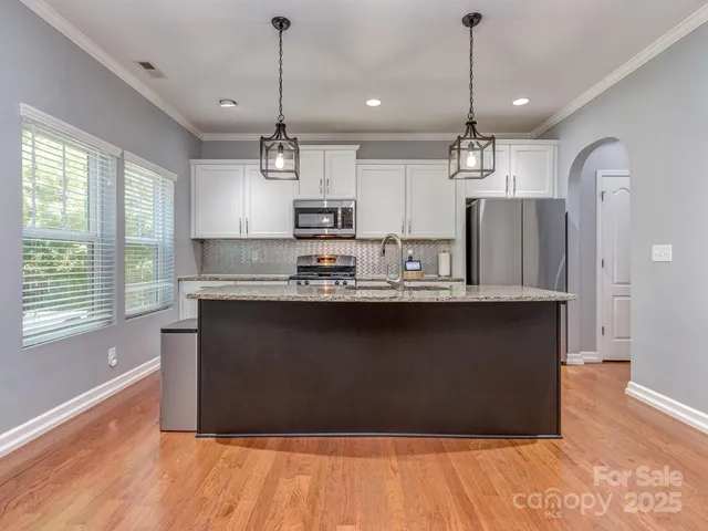 a kitchen with kitchen island stainless steel appliances a refrigerator sink and wooden floor