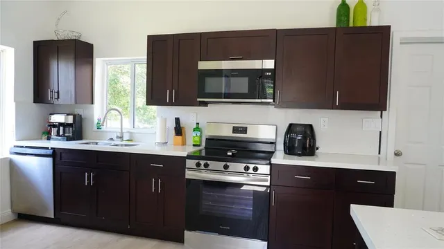 a kitchen with stainless steel appliances a stove a microwave a sink and cabinets