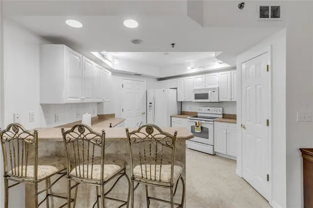 a kitchen with stainless steel appliances granite countertop white cabinets and a stove a refrigerator with white cabinets
