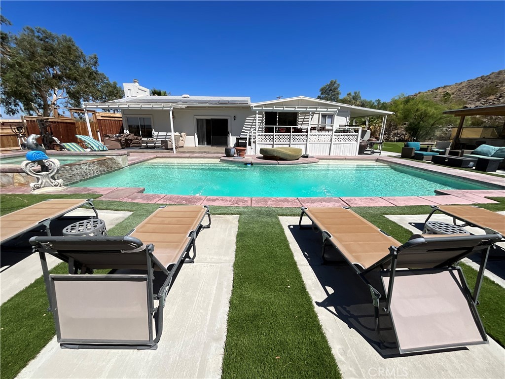 a view of a swimming pool with lawn chairs and a yard