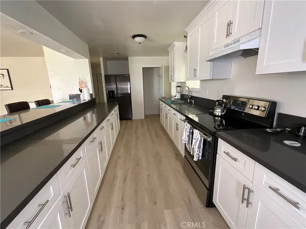 a kitchen with granite countertop a stove a sink dishwasher and cabinets with wooden floor