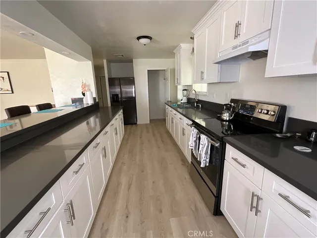 a kitchen with granite countertop a stove a sink dishwasher and cabinets with wooden floor