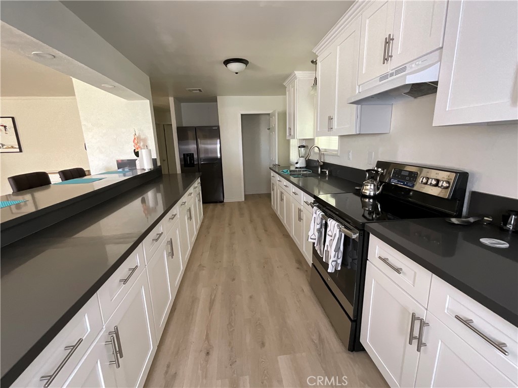 73405 Rask Road Desert Hot Springs, CA 92241 - Photo 18 of 26 a kitchen with granite countertop a stove a sink dishwasher and cabinets with wooden floor