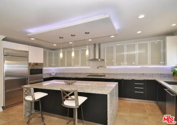 a kitchen with stainless steel appliances granite countertop a stove a sink a refrigerator and chairs