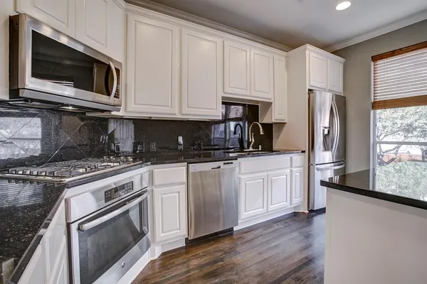 a kitchen with white cabinets and stainless steel appliances