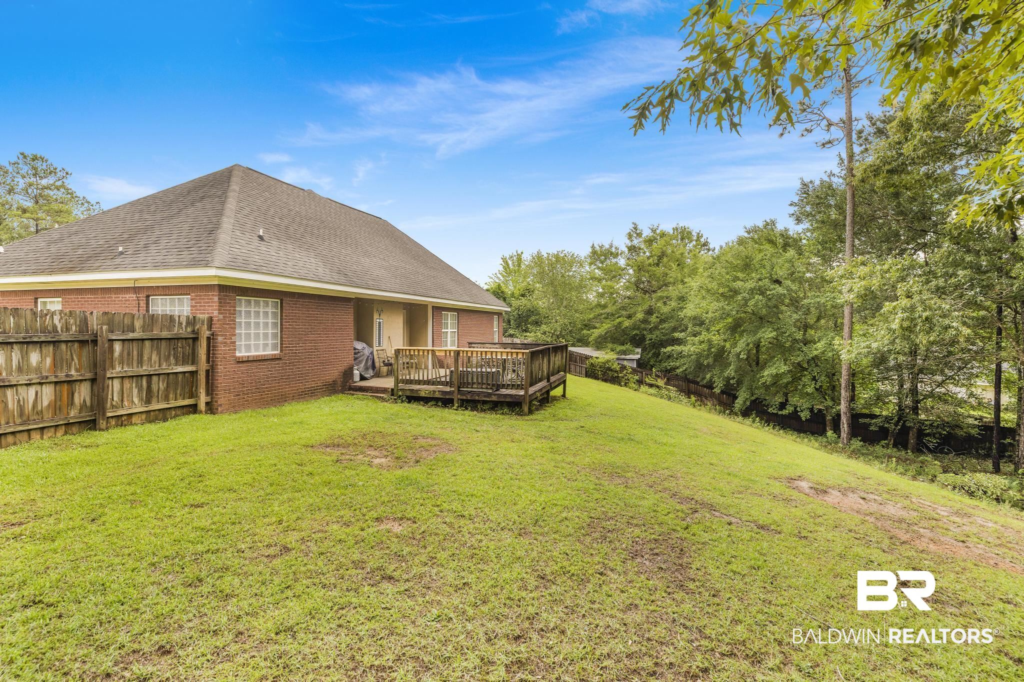 35814 Delvan Lane Bay Minette, AL 36507 - Photo 47 of 53 Expansive green lawn with a wooden privacy fence, a brick exterior, and a multi-level wooden deck
