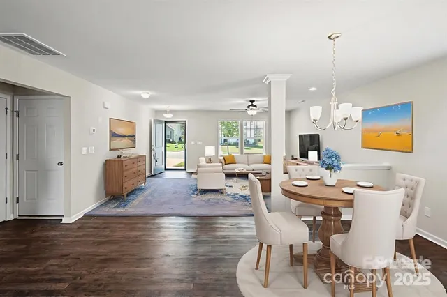 a living room with couches chairs and kitchen view with wooden floor