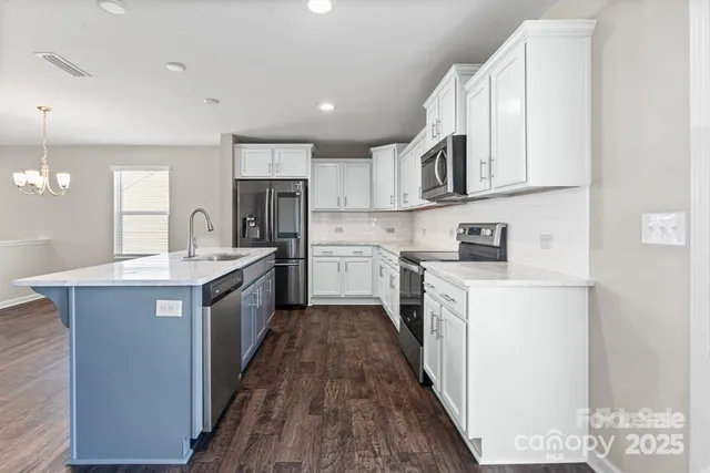 a kitchen with stainless steel appliances granite countertop a stove top oven a sink dishwasher and a refrigerator with wooden floor