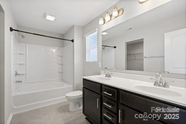 a bathroom with a granite countertop sink a toilet a mirror a bathtub and shower