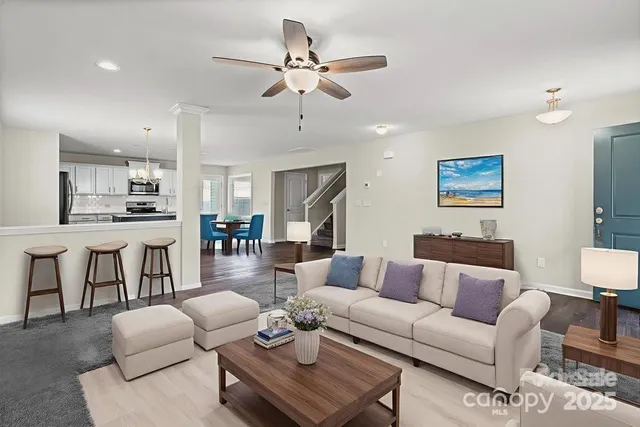 a living room with furniture kitchen view and a wooden floor