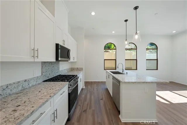 a kitchen with granite countertop a sink a counter top space stainless steel appliances and cabinets