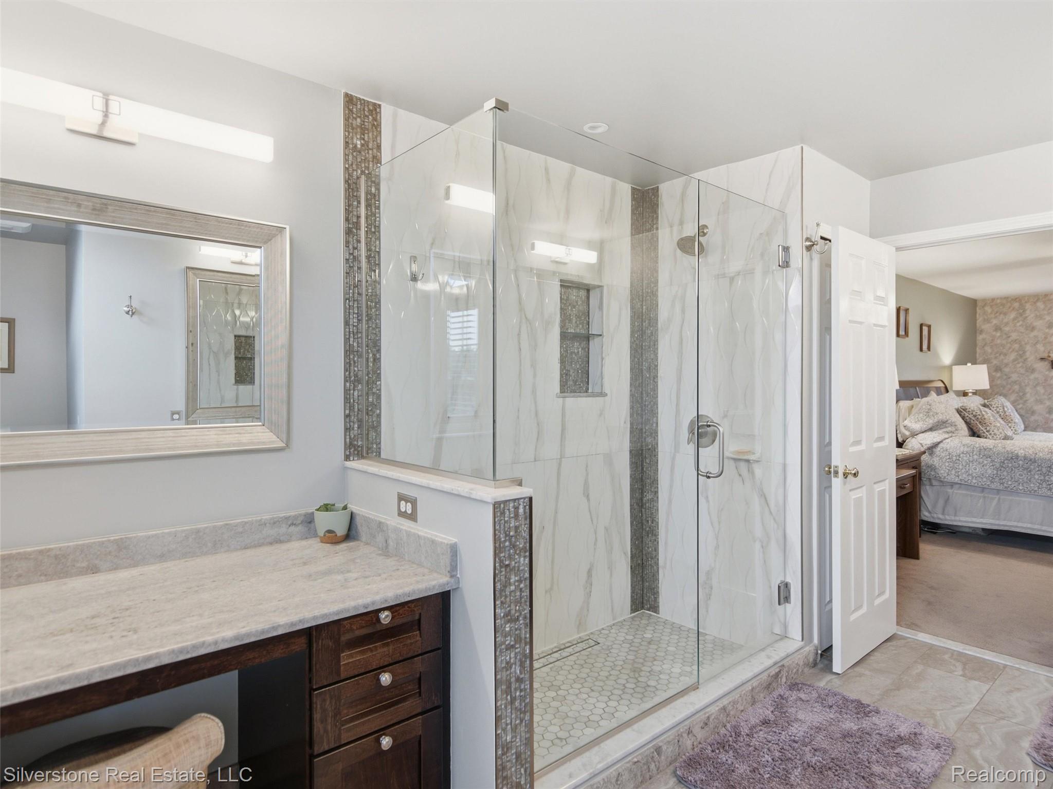 6577 Edith Court Troy, MI 48085 - Photo 36 of 61 Glass-enclosed shower with white marble-look tile, a vertical accent tile strip, and a hexagonal tile floor