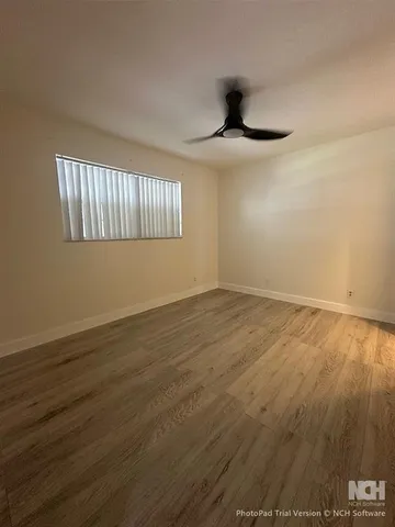 a view of an empty room with window and wooden floor
