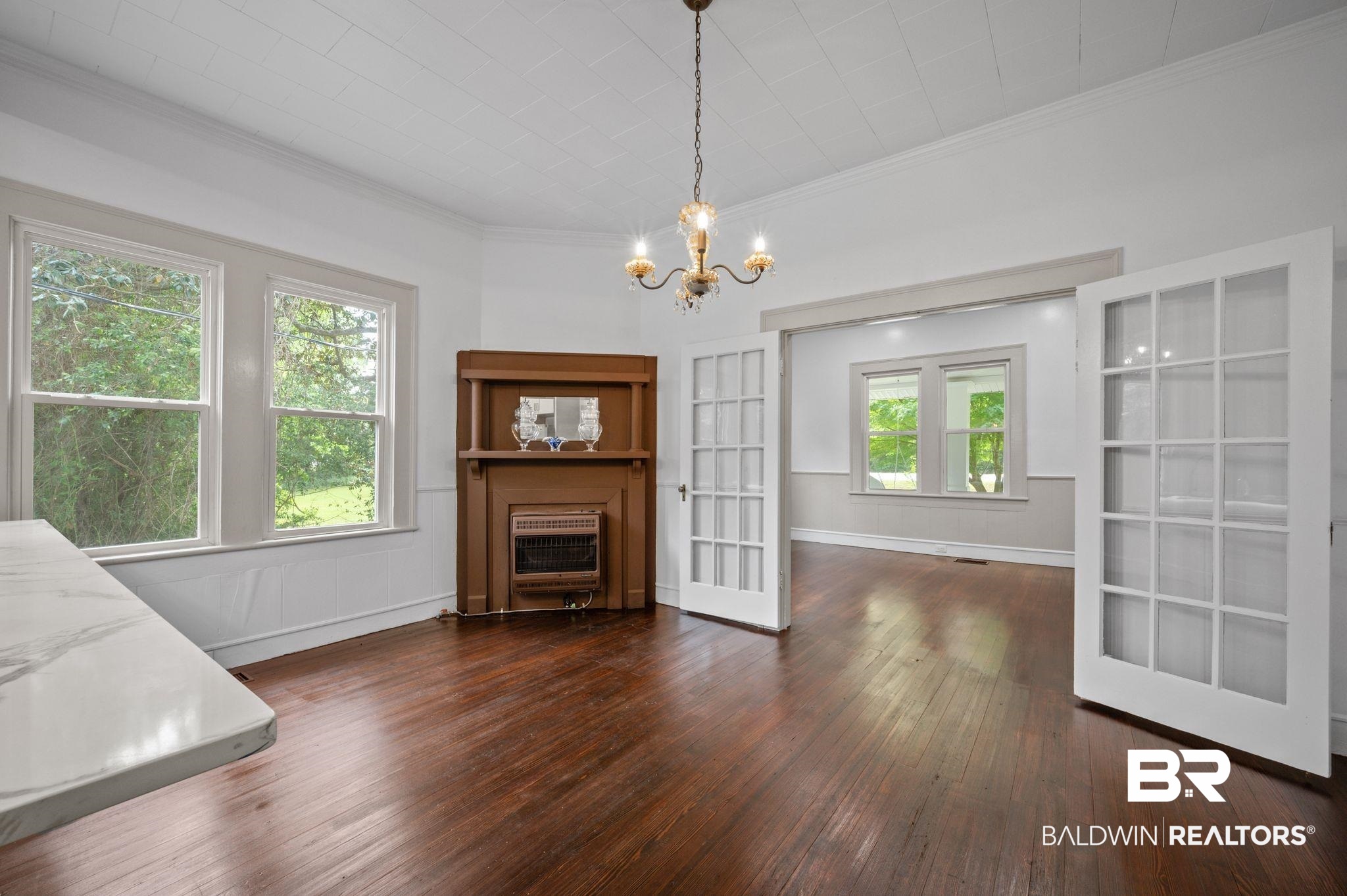 733 Pineville Road Monroeville, AL 36460 - Photo 14 of 68 Unfurnished dining area featuring wood-type flooring, ornamental molding, a fireplace, baseboards, and a chandelier