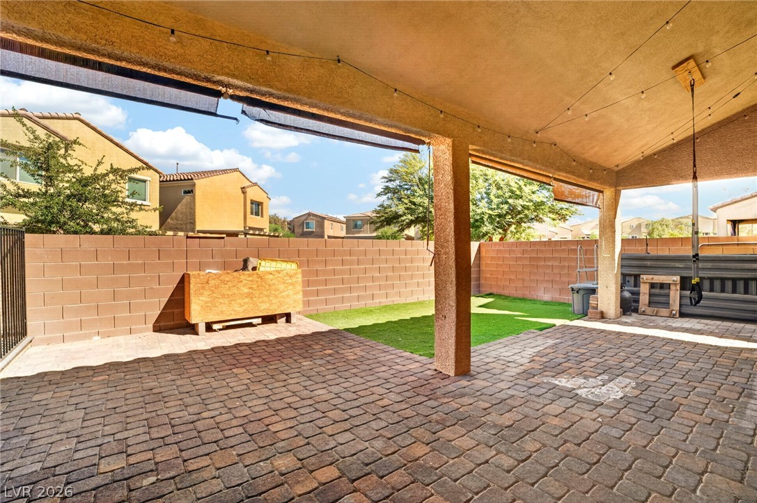 6281 Angora Peak Lane Las Vegas, NV 89115 - Photo 31 of 34 A private backyard oasis features a paved patio area and vibrant green lawn, ideal for outdoor relaxation.