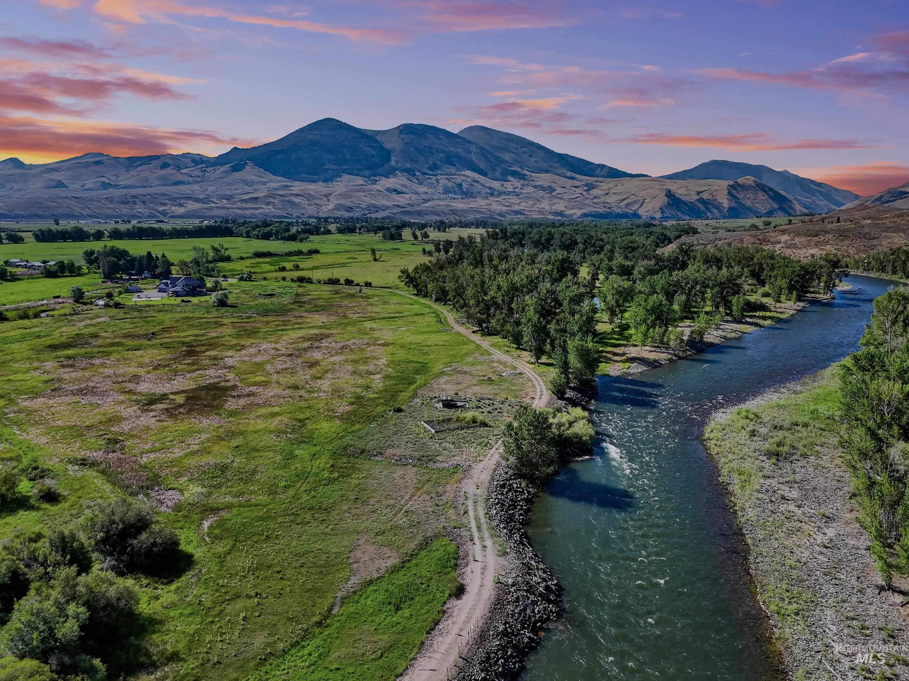 63 Mountain View Road Salmon, ID 83467 - Photo 4 of 50 Expansive riverfront property featuring a winding waterway, lush green fields, mature trees, and mountainous terrain