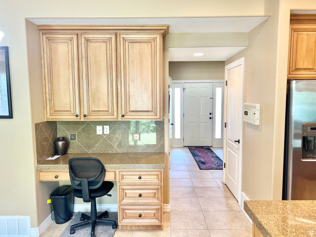 369 Culross Circle Tooele, UT 84074 - Photo 13 of 54 Built-in desk area featuring light wood cabinetry with upper storage, a stone-look countertop, and a tiled backsplash