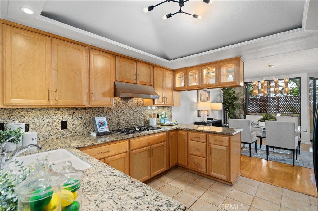 11687 Bellagio Road, Unit 12 Los Angeles, CA 90049 - Photo 15 of 50 The kitchen features glass front cabinetry with integrated lighting, stainless hood, GE Profile cooktop, and more.