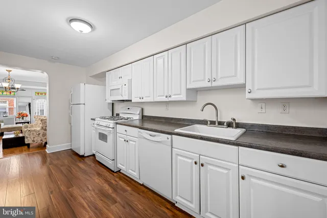 a kitchen with granite countertop white cabinets and white appliances