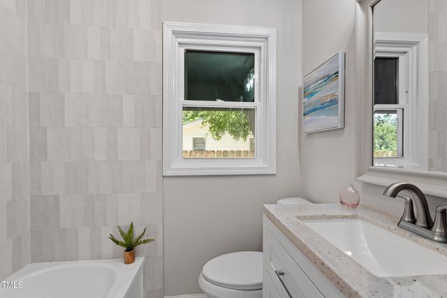 a bathroom with a granite countertop sink a toilet and tub
